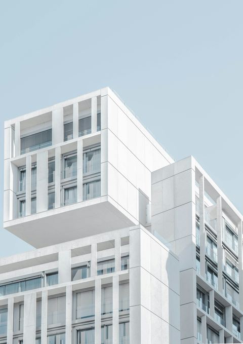 Edifício branco formado por módulos retangulares deslocados, contra o céu claro.