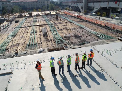 Equipe reunida sobre uma grande laje em construção, vista do alto.