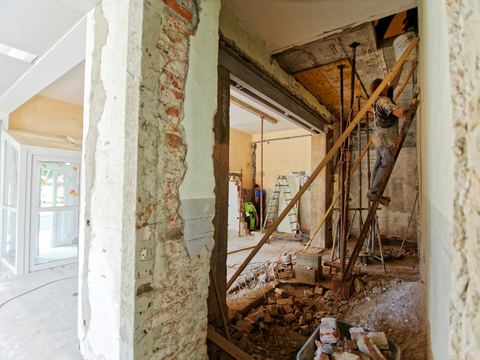 Ambiente interno em reforma, com paredes abertas e materiais de obra.